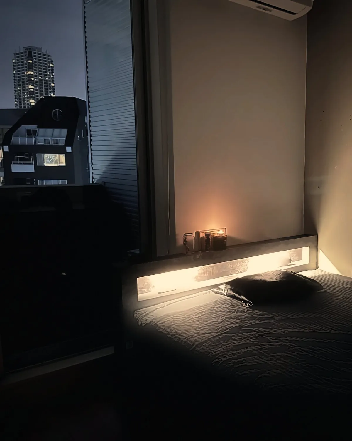 窓の外に夜景が見える施術室と、間接照明に照らされたベッド
